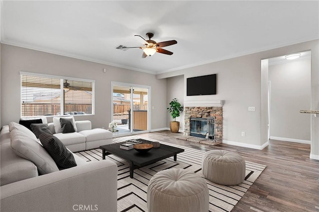 living area featuring light wood-type flooring, crown molding, and a stone fireplace