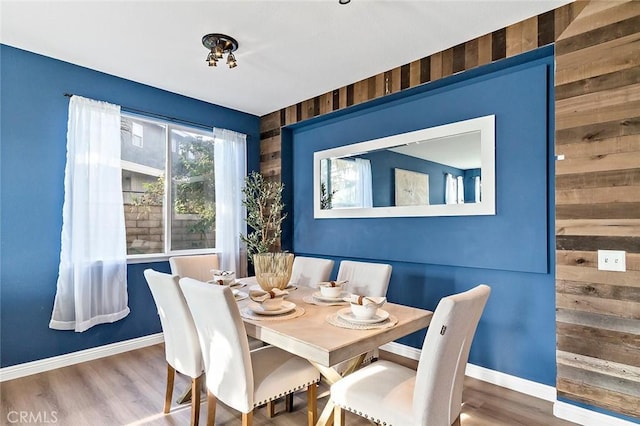 dining area with hardwood / wood-style flooring and wood walls