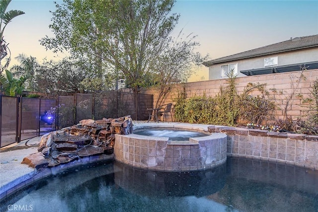 pool at dusk with an in ground hot tub