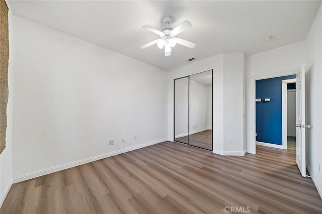 unfurnished bedroom featuring ceiling fan, hardwood / wood-style floors, and a closet