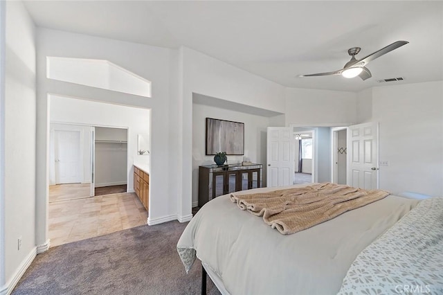 bedroom featuring carpet, a spacious closet, lofted ceiling, and ceiling fan