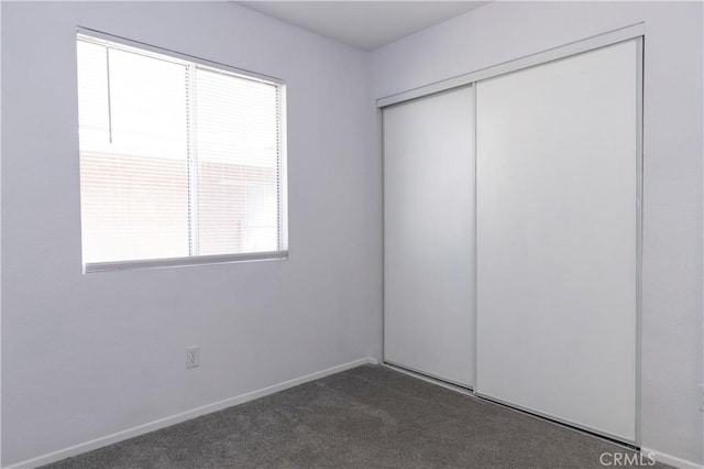 unfurnished bedroom featuring dark carpet and a closet