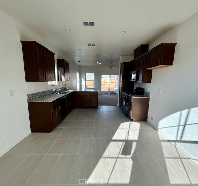 kitchen with light tile patterned floors, gas range, sink, and ceiling fan