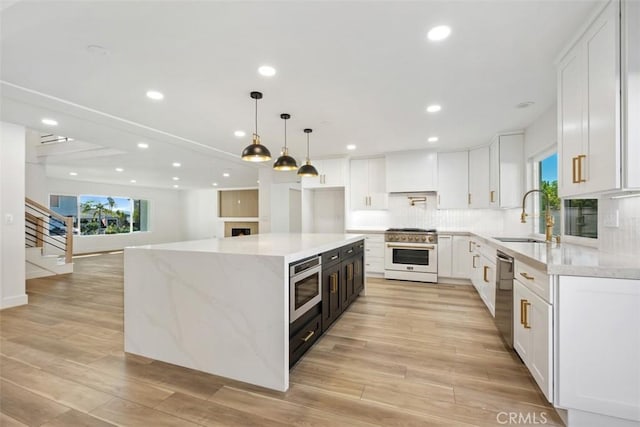 kitchen featuring appliances with stainless steel finishes, pendant lighting, white cabinetry, sink, and a large island