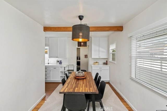 dining space featuring beamed ceiling and hardwood / wood-style floors