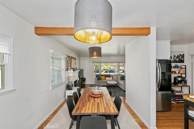 dining space featuring beamed ceiling and light hardwood / wood-style flooring