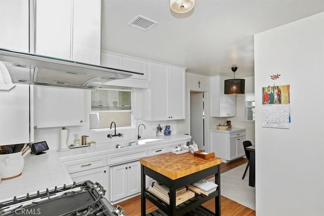 kitchen with white cabinetry, island range hood, pendant lighting, and light hardwood / wood-style floors