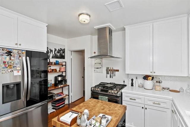 kitchen featuring white cabinetry, wall chimney range hood, and stainless steel appliances