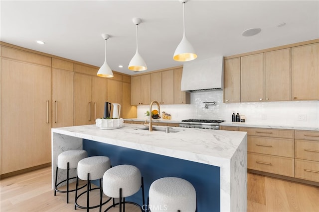 kitchen featuring an island with sink, sink, and light brown cabinetry