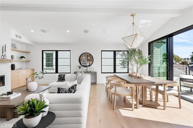 living room featuring a fireplace, lofted ceiling with beams, and light wood-type flooring