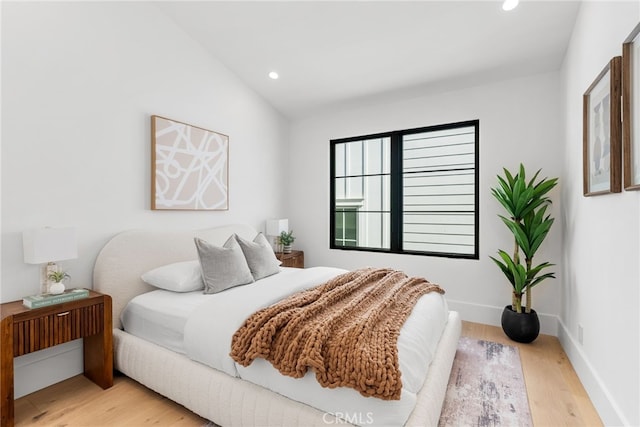 bedroom featuring lofted ceiling and light hardwood / wood-style flooring