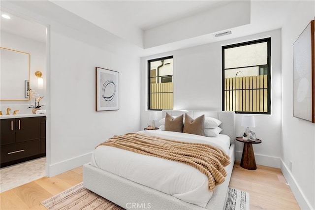 bedroom with sink, light hardwood / wood-style flooring, and ensuite bathroom