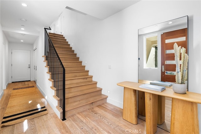 staircase with baseboards, wood finished floors, and recessed lighting