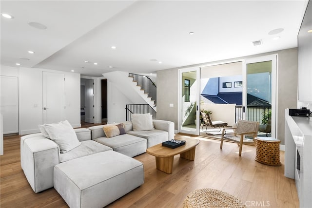 living area featuring stairway, light wood-type flooring, visible vents, and recessed lighting