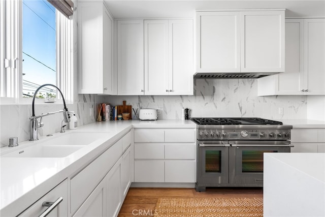 kitchen with white cabinets, sink, tasteful backsplash, and range with two ovens