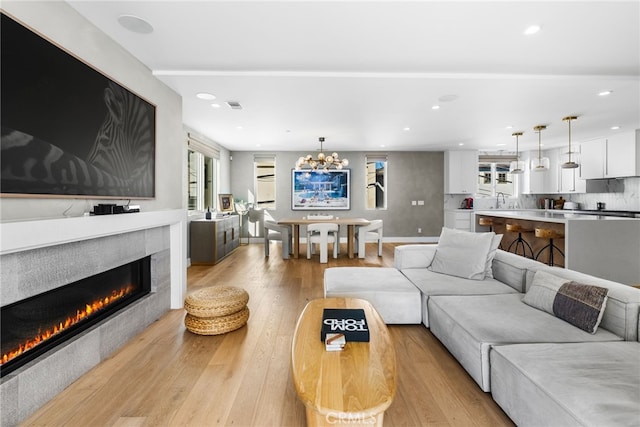 living area featuring a notable chandelier, light wood finished floors, recessed lighting, visible vents, and a tile fireplace