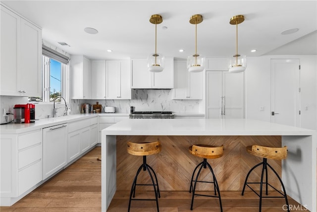 kitchen with decorative light fixtures, white cabinetry, a kitchen bar, and a center island