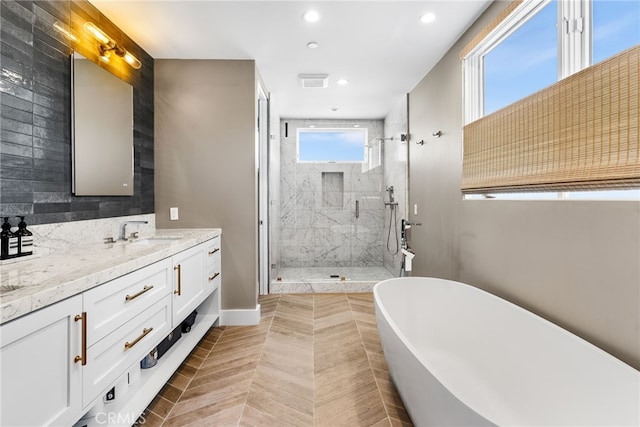 full bath featuring recessed lighting, a freestanding tub, vanity, and a marble finish shower