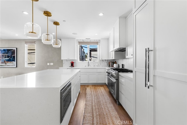 kitchen with hardwood / wood-style floors, white cabinetry, pendant lighting, a kitchen island, and high end stove