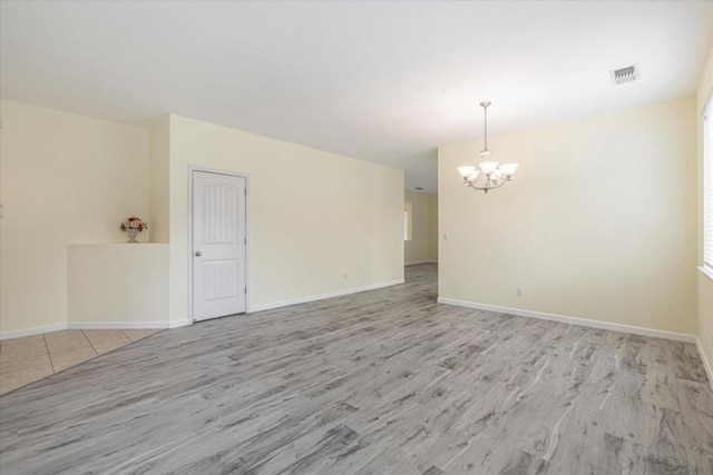 unfurnished room featuring light wood-type flooring and a chandelier