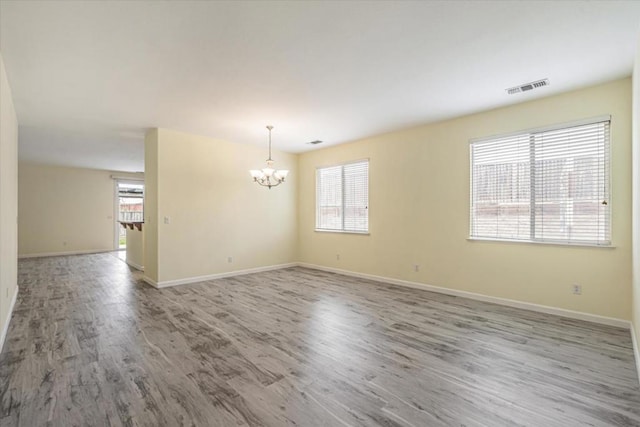 spare room with hardwood / wood-style flooring and a notable chandelier