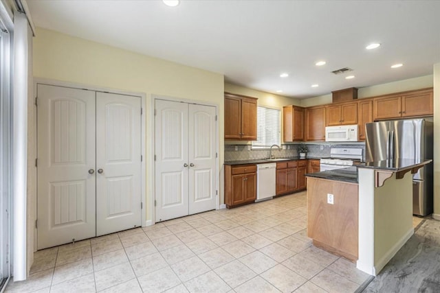 kitchen featuring a breakfast bar, sink, backsplash, a center island, and white appliances