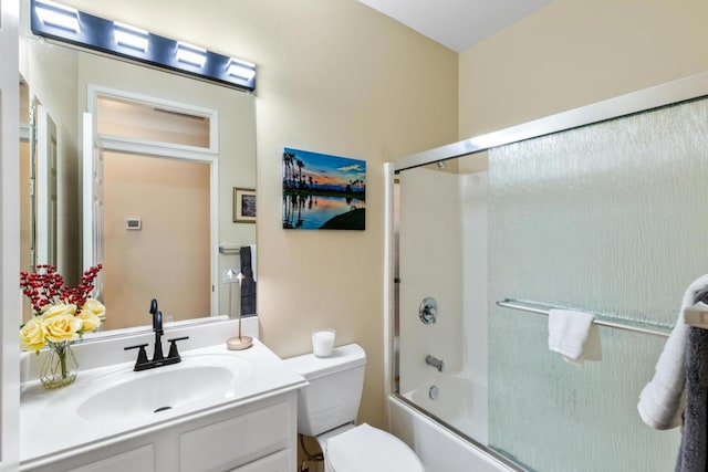 full bathroom with bath / shower combo with glass door, vanity, and toilet