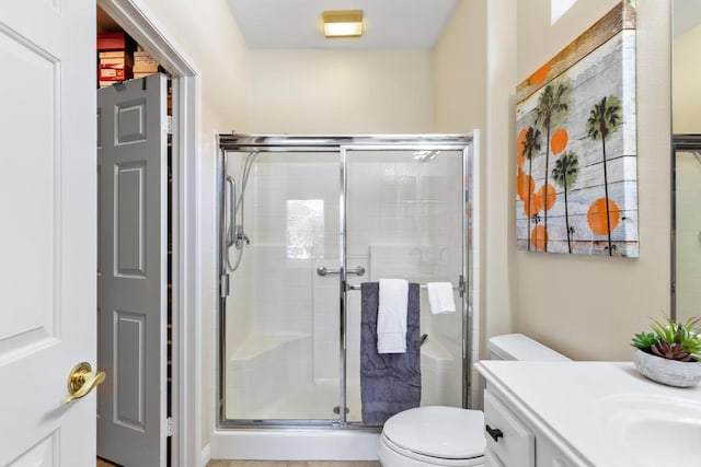 bathroom featuring vanity, toilet, and a shower with shower door