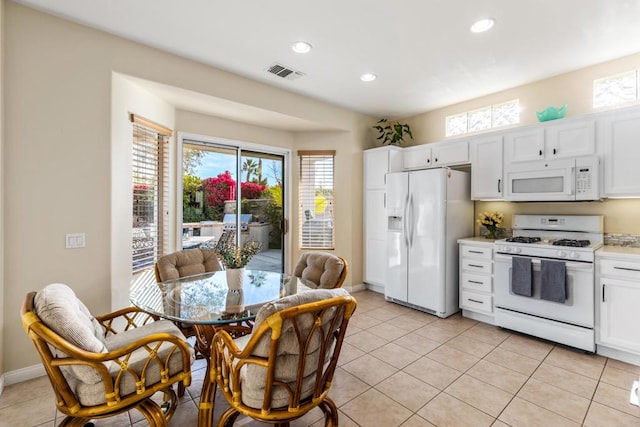 kitchen featuring light tile patterned floors, white cabinets, and white appliances