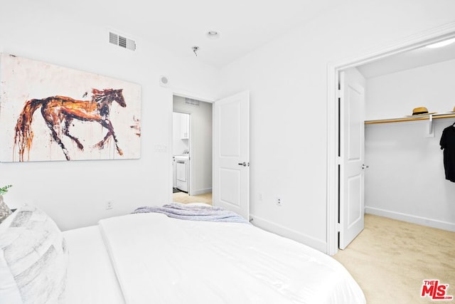 carpeted bedroom with washer / dryer and a spacious closet