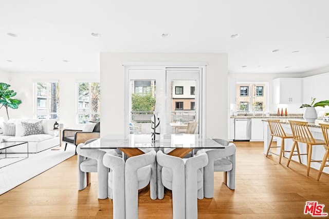 dining room featuring sink, light hardwood / wood-style flooring, and a healthy amount of sunlight