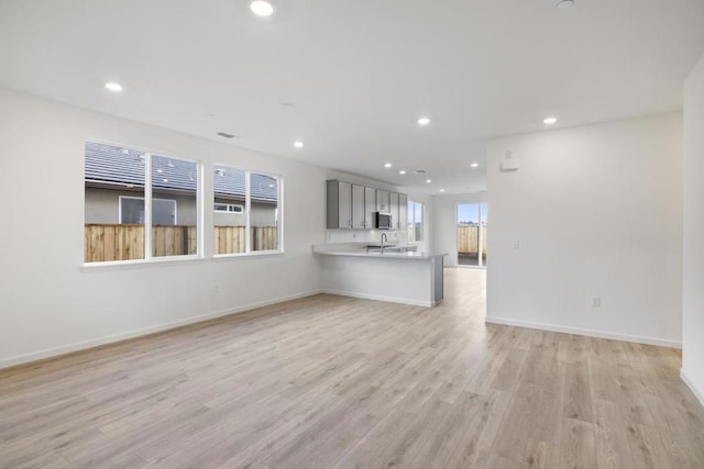 unfurnished living room with sink and light hardwood / wood-style flooring