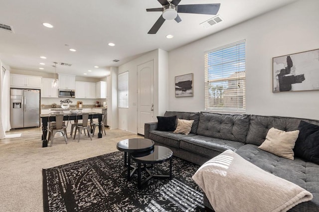 carpeted living room with ceiling fan