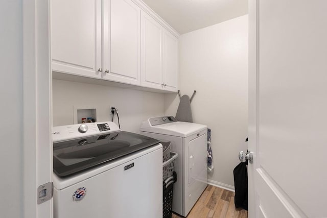 washroom with cabinets, separate washer and dryer, and light hardwood / wood-style flooring