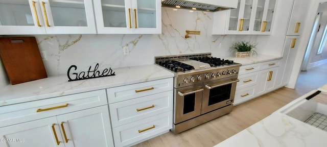 kitchen featuring range with two ovens, premium range hood, and white cabinetry