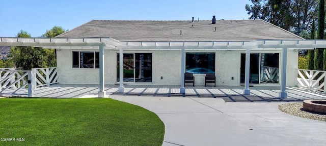 rear view of property featuring a pergola, a patio, and a lawn