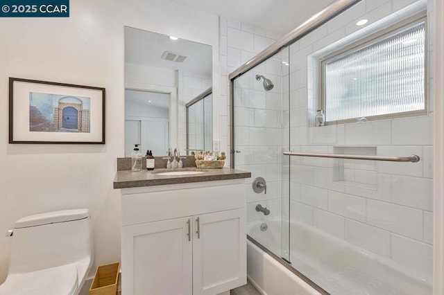 full bathroom with vanity, toilet, and combined bath / shower with glass door