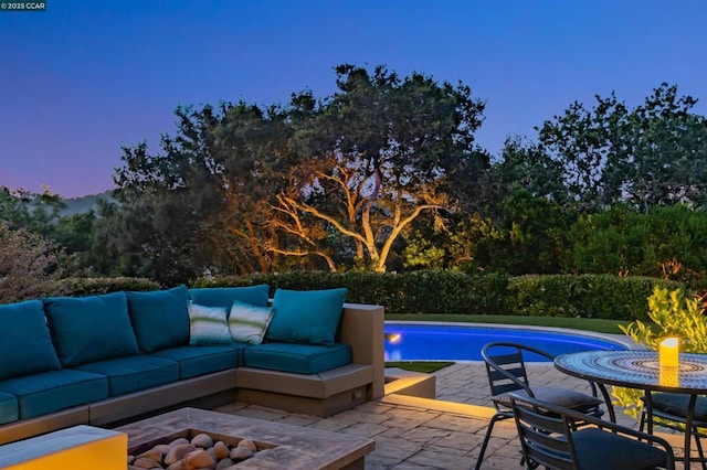 pool at dusk with an outdoor living space and a patio