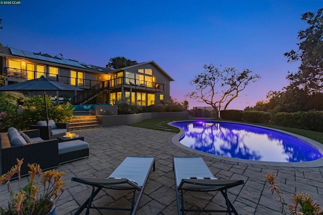 pool at dusk featuring an outdoor living space and a patio area