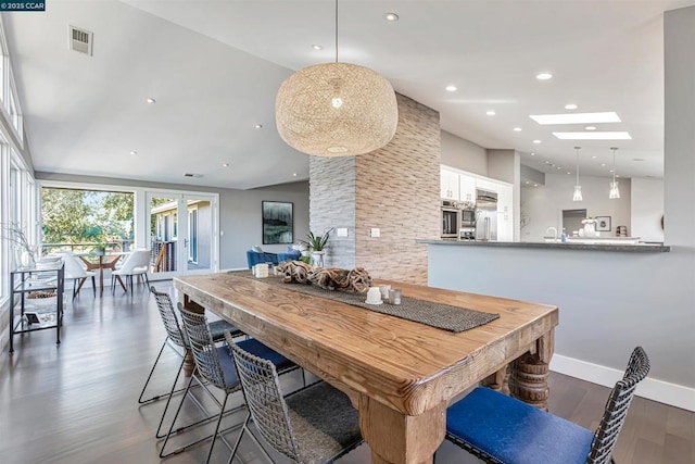 dining room featuring dark wood-type flooring, a skylight, and high vaulted ceiling