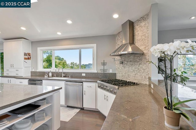 kitchen with wall chimney range hood, sink, white cabinets, and appliances with stainless steel finishes