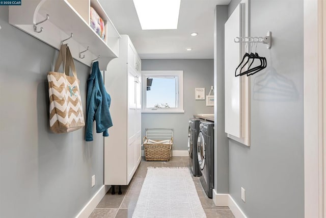 laundry area with a skylight, washer and dryer, and light tile patterned floors