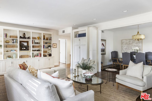 living room with crown molding, hardwood / wood-style flooring, and an inviting chandelier