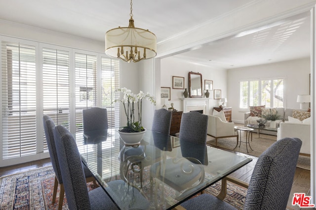 dining space featuring crown molding, wood-type flooring, and an inviting chandelier