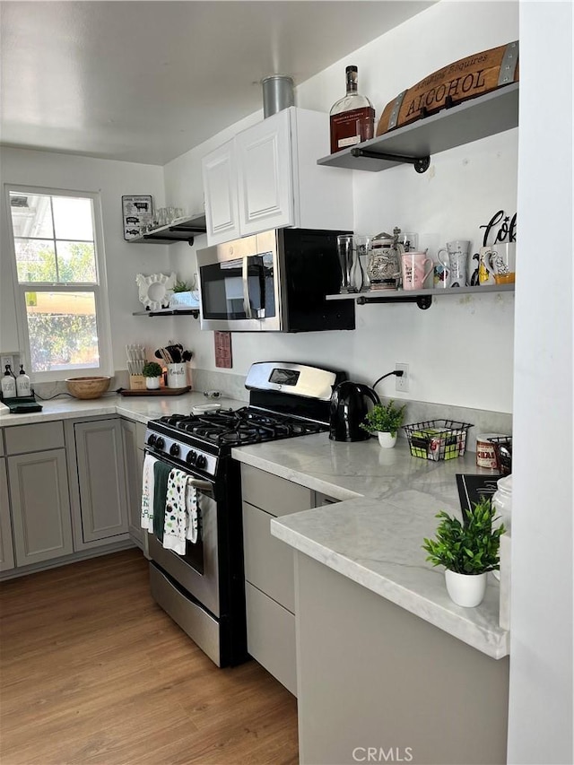 kitchen with gray cabinetry, stainless steel appliances, and light wood-type flooring