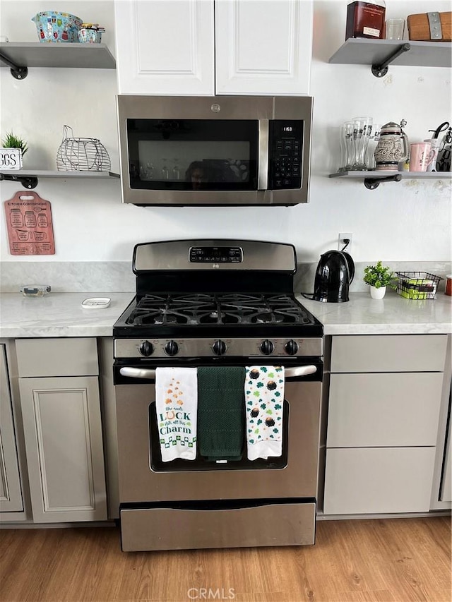 kitchen featuring appliances with stainless steel finishes, gray cabinets, and light wood-type flooring