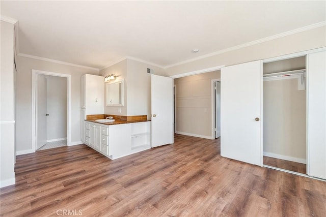 kitchen featuring white cabinetry, wood-type flooring, sink, and ornamental molding