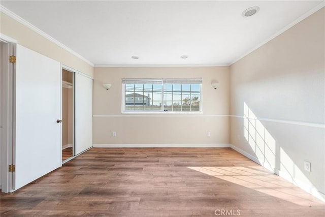 unfurnished bedroom with crown molding, wood-type flooring, and a closet