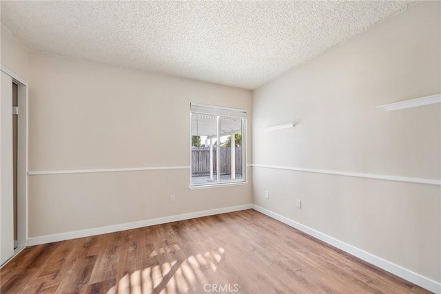 unfurnished room featuring wood-type flooring and a textured ceiling