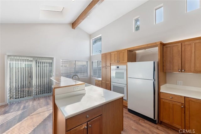 kitchen featuring sink, a center island, high vaulted ceiling, white appliances, and beam ceiling